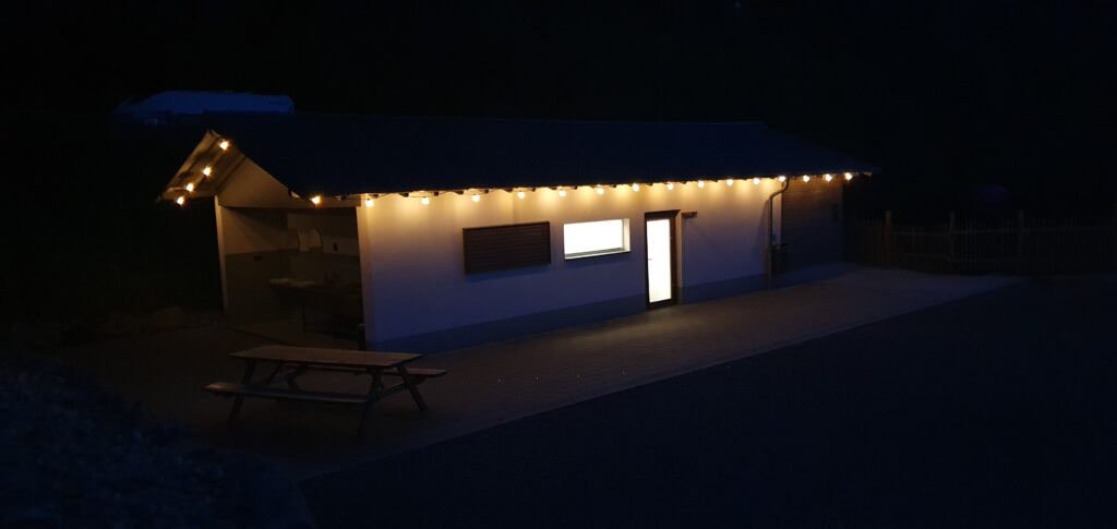 Camping Eifel. Wildbach Camping Hellenthal-Eifel 2026. Neuigkeiten für Camper 5 Parzellen Waldlichtung Sanitärgebäude bei Nacht